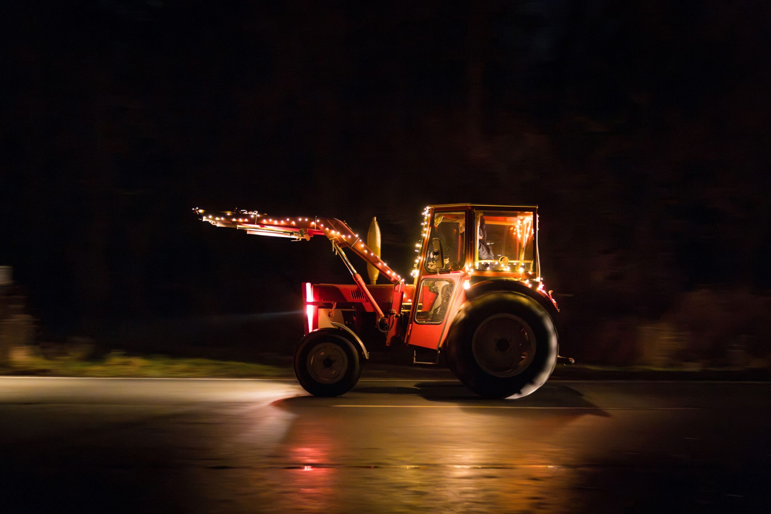 Ein Traktor bei Dunkelheit, der durch seine Beleuchtung gut sichtbar ist