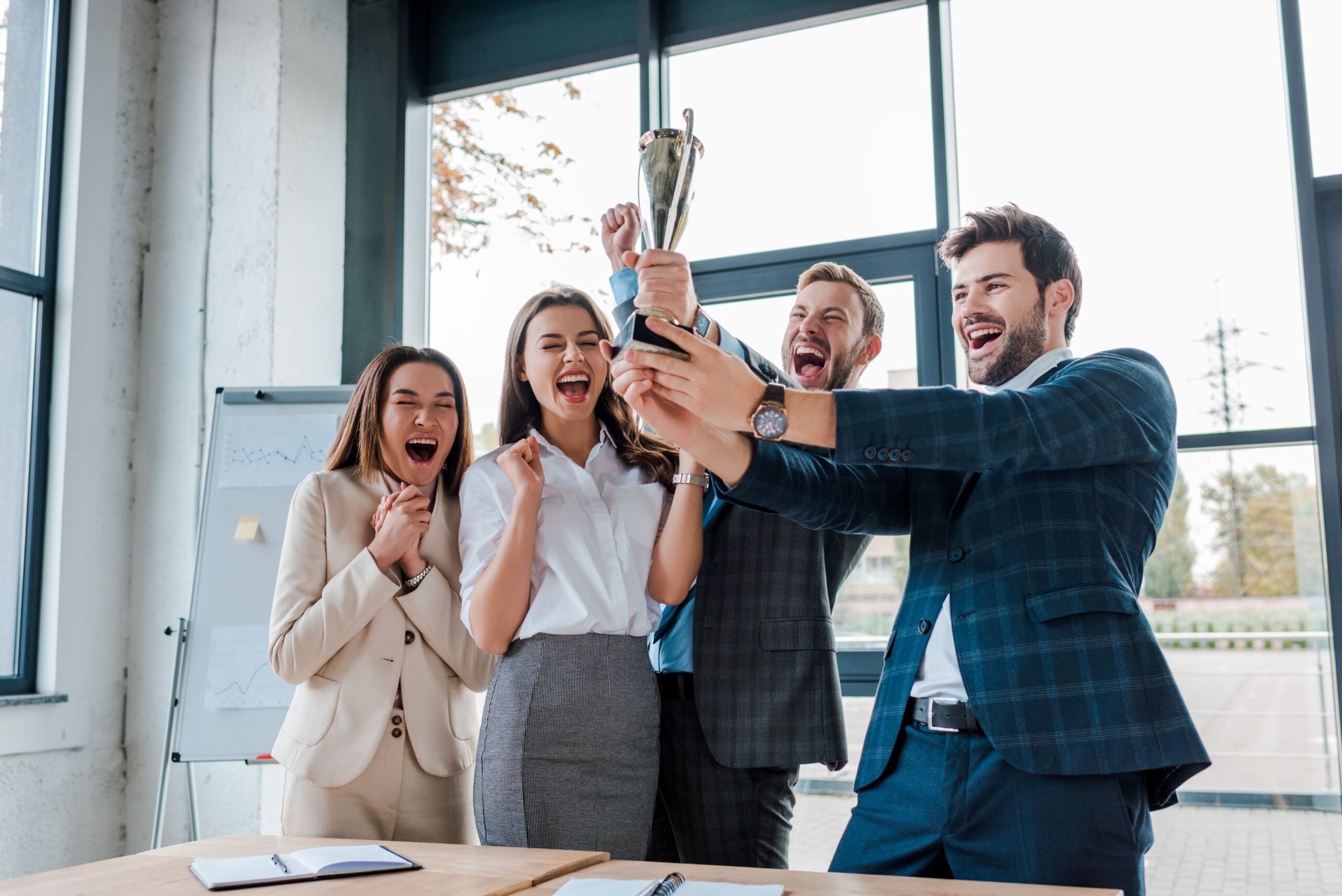 Business-Team feiert Auszeichnung mit Pokal im Büro als Zeichen beruflicher Wertschätzung