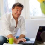 Mann bestellt Pokale online mit dem Laptop in entspannter Atmosphäre zu Hause