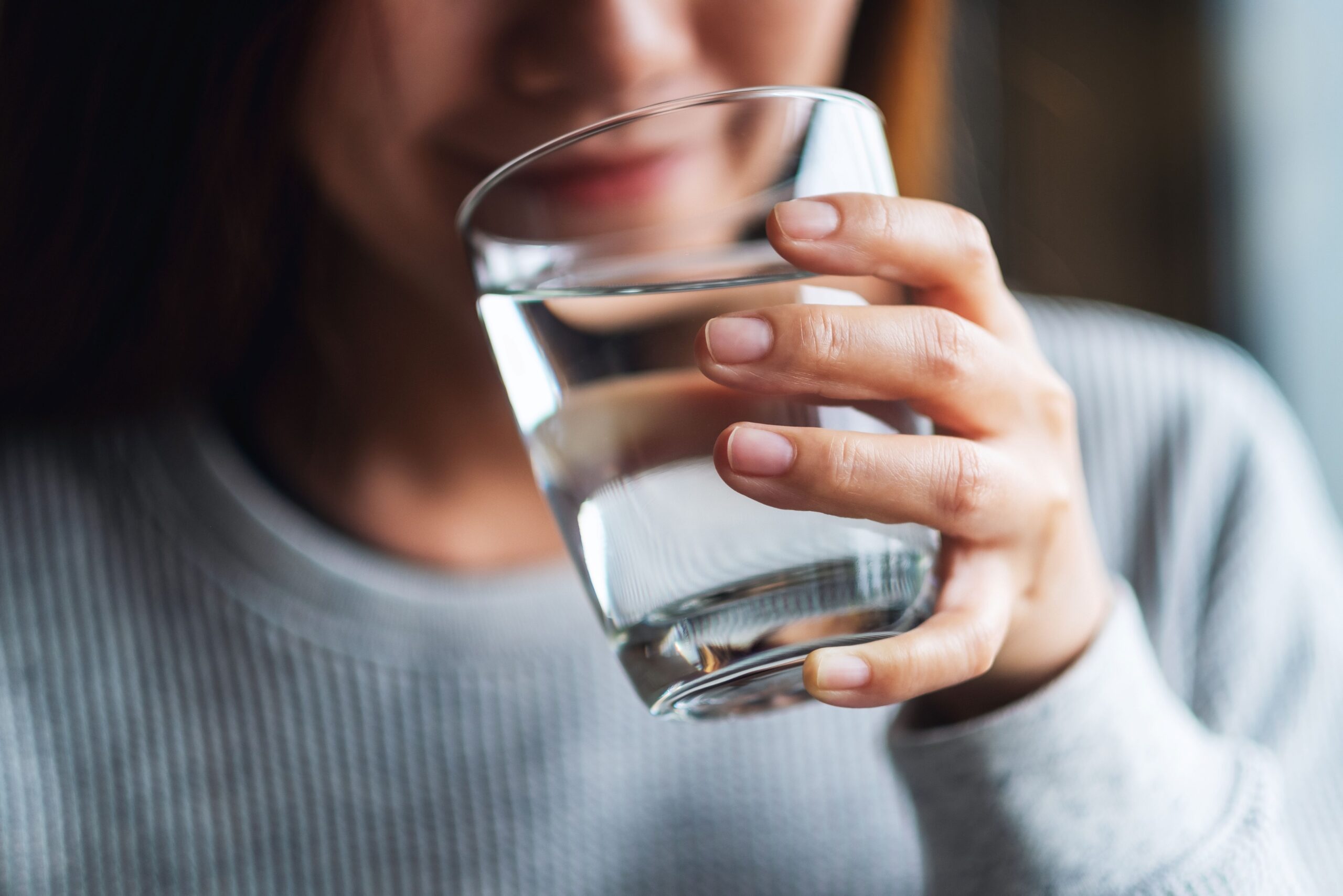 Frau hält Glas mit klarem Wasser in der Hand