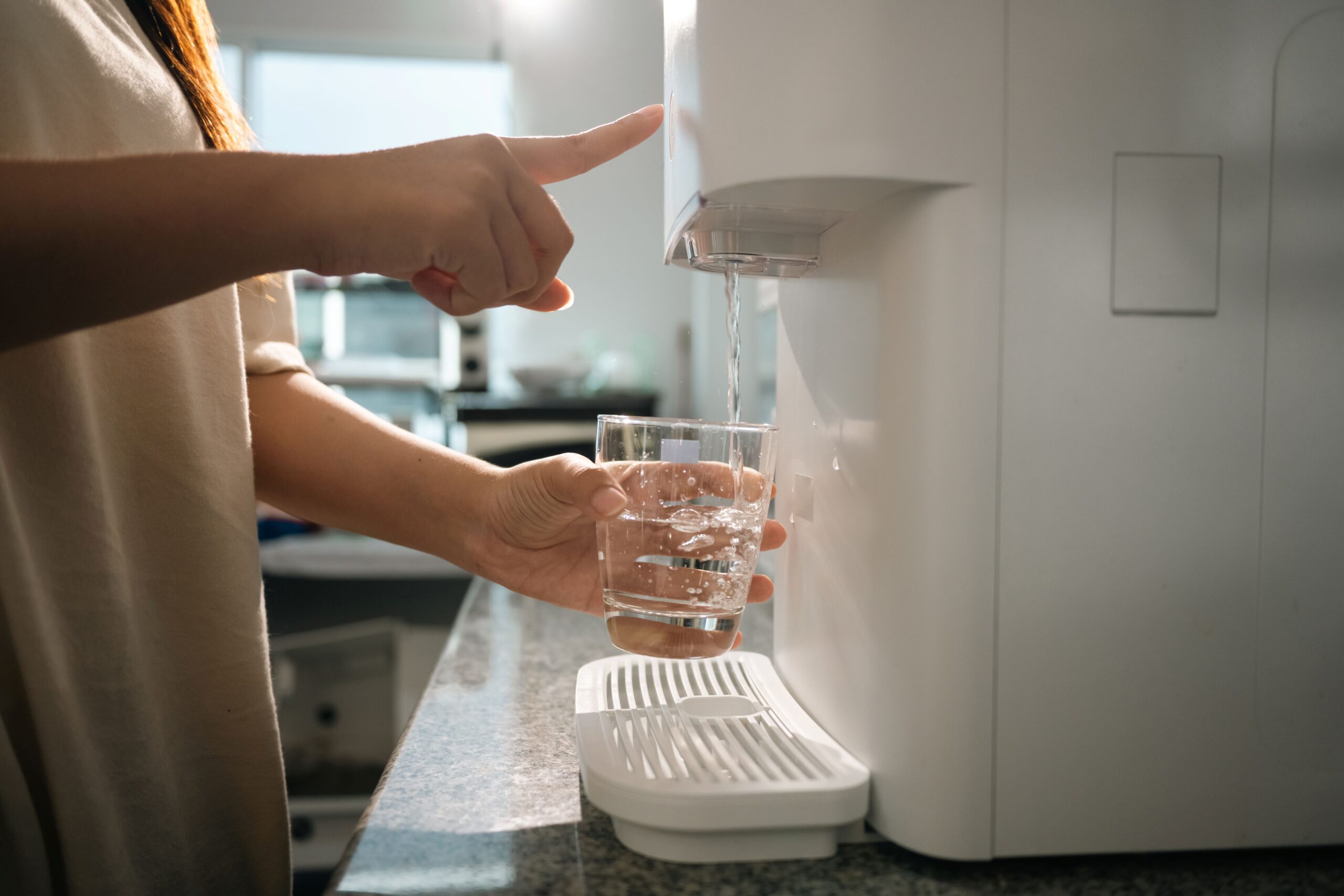 Person zapft frisches Wasser aus moderner Auftisch Osmoseanlage